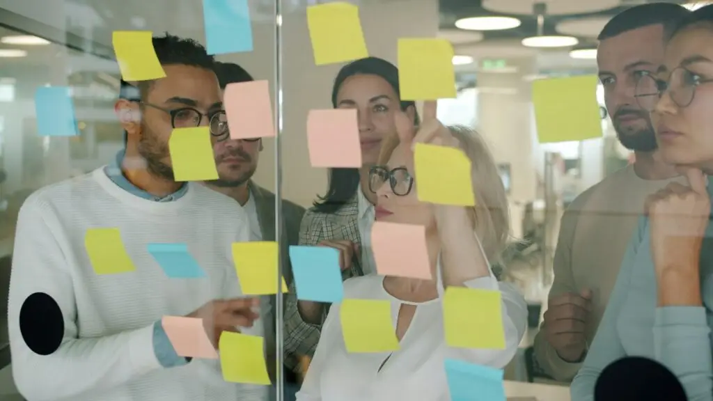 Team planning a project with sticky notes on a glass wall